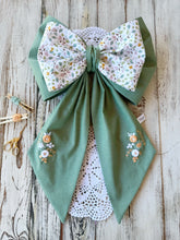 Carica l'immagine nel visualizzatore di Gallery, FIOCCO NASCITA PERSONALIZZATO base verde con bamboline e nome ricamato a mano